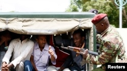 A policeman guards suspected Somali illegal migrants arrested at a holding station in Kenya's capital Nairobi, April 7, 2014.