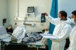 FILE - Staff of the Afghan-Japan Hospital look at a chest X-ray in the COVID-19 emergency ward section next to a patient in Kabul, Afghanistan, Dec. 9, 2021.