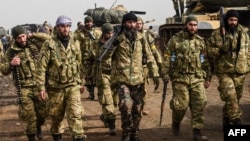 Syrian opposition fighters backed by Turkey walk in front of Turkish troops near the Syria border at Hassa, Hatay province on Jan. 22, 2018.