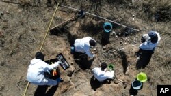FILE - Forensic technicians excavate a field on a plot of land referred to as a cartel "extermination site" where burned human remains are buried, on the outskirts of Nuevo Laredo, Mexico, Feb. 8, 2022.