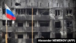 一面俄罗斯旗帜竖立在乌克兰马里乌波尔一座被炸成废墟的建筑前。（2022年4月12日）