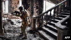 A Russian soldier patrols at the Mariupol drama theater that was bombed last March 16, in Mariupol. This picture was taken during a trip organized by the Russian military on April 12, 2022. (Photo by Alexander NEMENOV / AFP)
