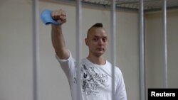 FILE - Ivan Safronov, a former journalist and an aide to the head of Russia's space agency Roscosmos who remains in custody on state treason charges, gestures inside a defendants' cage as he attends a court hearing in Moscow, Russia, Sept. 2, 2020. 