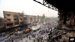 Petugas keamanan Irak dan warga setempat berkumpul di lokasi bom bunuh diri di Karada, pusat perbelanjaan di tengah kota Baghdad, Irak, Minggu, 3 Juli 2016. Puluhan orang tewas dan lebih dari 100 orang luka-luka dalam dua serangan terpisah di ibukota Irak Minggu pagi, kata pejabat Irak. (AP Photo/Hadi Mizban)