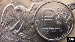 FILE - A Russian ruble coin is pictured with U.S. currency in Moscow, March 15, 2022.
