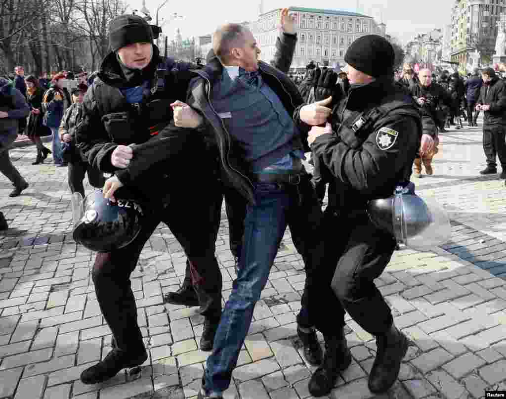 A counter-demonstrator is detained by riot police as activists take part in a rally for gender equality and against violence towards women on International Women's Day in Kiev, Ukraine, March 8, 2019. 