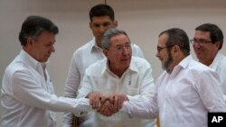 Cuba's President Raul Castro, center, encourages Colombian President Juan Manuel Santos, left, and Commander the Revolutionary Armed Forces of Colombia or FARC, Timoleon Jimenez, known as "Timochenko," to shake hands, in Havana, Cuba, Sept. 23, 2015.