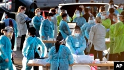 Petugas medis bersiap melakukan tes Covid-19 terhadap ratusan orang yang antre dengan kendaraan mereka di kawasan barat Maryvale, Phoenix, Amerika, 27 Juni 2020. (Foto: dok).