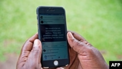 FILE - A woman scrolls through her social media account on her phone in Kampala, July 5, 2018. Uganda's Communications Commission issued a notice this week requiring anyone wishing to publish information online to first be licensed.