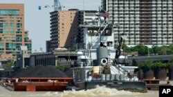 A small, but mighty, tugboat pushes a barge loaded with coal up the Ohio River, past downtown Louisville, Kentucky.