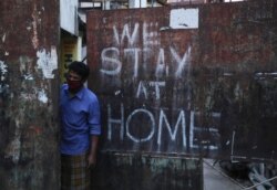 FILE - An Indian wearing a face mask looks out from a gate during lockdown to prevent the spread of new coronavirus in Hyderabad, India, April 18, 2020.