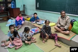 People sit in a school being used as a shelter during Typhoon Noru in Hoi An on September 27, 2022. - Vietnam has tried to evacuate people ahead of the arrival of typhoon Noru, one of the biggest to make landfall in the country, officials said on September 27. (Photo by Nhac NGUYEN / AFP)