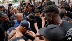 Players and officials of the soccer club Arema FC pray outside the Kanjuruhan Stadium where many fans lost their lives in a stampede Saturday night in Malang, Indonesia, Oct. 3, 2022. 