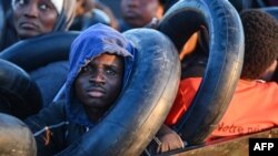 Migrants from sub-Saharan Africa sit in a makeshift boat that was being used to clandestinely make its way towards the Italian coast, as they are found by Tunisian authorities about 50 nautical miles in the Mediterranean Sea off the coast of Tunisia's cen