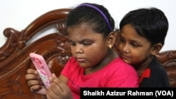 Two elementary school students are seen captivated by a mobile phone, Oct. 11, 2022. School children used mobile phones to study online during the COVID lockdowns in India and many of them have now turned into what some call "mobile phone addicts."