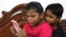Two elementary school students are seen captivated by a mobile phone, Oct. 11, 2022. School children used mobile phones to study online during the COVID lockdowns in India and many of them have now turned into what some call "mobile phone addicts."