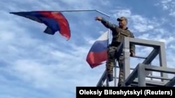 A member of the Ukrainian troop brings down a Donetsk Republic flag hoisted on a monument in Lyman, Ukraine in this screen grab obtained from social media video released on Oct. 1, 2022.
