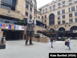 Shoppers are seen by the Mandela statue at Nelson Mendela Square in the Johannesburg neighborhood of Sandton, South Africa, Oct. 27, 2022.