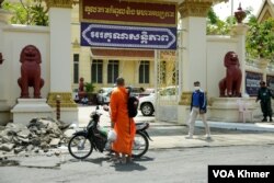 បុរសម្នាក់ដើរកាត់ខ្លោងទ្វារចូលរបស់តុលាការកំពូល នៅរាជធានីភ្នំពេញ ថ្ងៃទី ២៦ ខែតុលា ឆ្នាំ ២០២២។ (លាស់ លីបលីប/វីអូអេ)