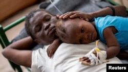 Karina Joseph, 19, comforts her 2-year-old child Holanda Sineus as she receives treatment for cholera in a tent at a Doctors Without Borders hospital in Cite Soleil, a densely populated commune of Port-au-Prince, Haiti, Oct. 15, 2022. 