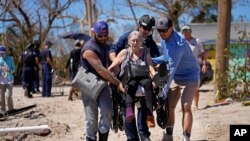 Rescuers help evacuate Suzanne Tomlinson, a resident who rode out the storm, as they carry her to a waiting boat in the aftermath of Hurricane Ian on Pine Island in Florida's Lee County, Oct. 2, 2022. 