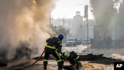 A firefighter helps a colleague escape a crater after a Russian attack in Kyiv, Ukraine, Oct. 10, 2022. Russia unleashed a lethal barrage of strikes on Monday, destroying civilian targets in several Ukrainian cities. The attack on Kyiv left cars burned, w