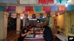 Artisans make "papel picado", the traditional manufacture of tissue paper cut-out decorations long used in altars for the Day of the Dead, in a workshop in Xochimilco, a borough of Mexico City, Oct. 27, 2022.