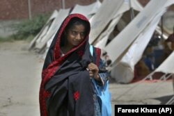 Flood victim Rajul Noor walks towards her tent school at a relief camp, in Dadu district, Pakistan, Sept. 23, 2022. (AP Photo/Fareed Khan)