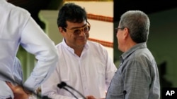 Ivan Danilo Rueda, High Commissioner for Peace on behalf of the Colombian government, center, shakes hands with Pablo Beltran of the Colombian guerrilla National Liberation Army (ELN) after a signing ceremony to resume peace talks.