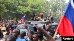 Burkina Faso's self-declared new leader Ibrahim Traore is welcomed by supporters holding Russian's flags as he arrives at the national television standing in an armoured vehicle in Ouagadougou, Oct. 2, 2022.