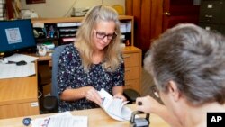 FILE - Carroll County Board of Elections Clerk Sarah Dyck, foreground, stamps incoming absentee ballot applications as Elections Clerk Deloris Kean counts more applications at the Board of Elections offices in Carrollton, Ohio, Sept. 26, 2022.