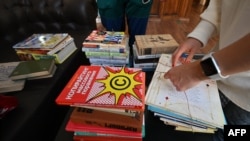 FILE - Julia Sydorenko and her husband tie up stacks of Russian language books which they brought to the Siayvo bookstore, where they are being collected and prepared for recycling, in Kyiv, Ukraine, Sept. 18, 2022.