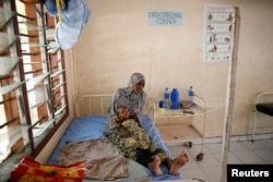 FILE - A Somali refugee holds a toddler at a hospital in the Dadaab refugee camp, Kenya, Dec. 19, 2017.