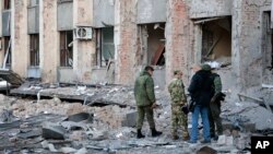 Investigators inspect a site after shelling near an administrative building, in Donetsk, the capital of Donetsk People's Republic, eastern Ukraine, Oct. 16, 2022. 