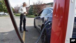 FILE - Bob Palrud of Spokane, Wash. speaks with a fellow electric vehicle owner who is charging up at a station along Interstate 90, on Wednesday Sept. 14, 2022, in Billings, Montana. (AP Photo/Matthew Brown)