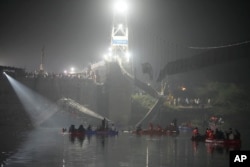 Rescuers on boats search in the Machchu river next to a cable suspension bridge that collapsed in Morbi town of western state Gujarat, India, Monday, Oct. 31, 2022. (AP Photo/Ajit Solanki)