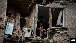 People gather their belongings from damaged house after an overnight Russian shelling in Konstantinovka, eastern Ukraine, Oct. 14, 2022.
