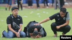 Reaksi para pemain dan ofisial Arema FC saat mereka mengunjungi Stadion Kanjuruhan, setelah terjadi kerusuhan dan kericuhan menyusul pertandingan sepak bola antara Arema vs Persebaya di Malang, Jawa Timur. (Foto: Antara / Prasetia Fauzani via Reuters)