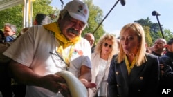 Pemimpin Brothers of Italy Giorgia Meloni melihat seorang petani membuat simpul mozzarella di acara asosiasi petani Italia desa Coldiretti, di Milan, Italia, Sabtu, 1 Oktober 2022. (AP Photo/Luca Bruno)