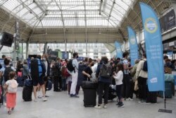 Pemudik mengantre untuk mengakses kereta api saat karyawan kereta api memeriksa kartu kesehatan COVID-19 yang dibutuhkan setiap orang di negara itu untuk masuk kafe, kereta api, dan tempat lainnya, Senin, 9 Agustus 2021. (Foto: AP)