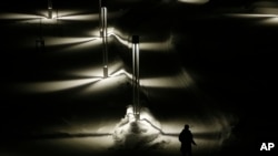 A pedestrian smokes a cigarette as she walks on a snow covered pathway in Alta, northern Norway, Monday, Feb. 1, 2016. (AP Photo/Alastair Grant)
