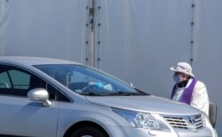 FILE PHOTO: A priest wearing a protective mask gives a "drive-in confession" in front of a church following the coronavirus disease (COVID-19) outbreak in Warsaw Poland, April 6, 2020. Adam Stepien/Agencja Gazeta via REUTERS/File Photo ATTENTION EDITORS