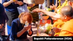 Buddhist monks pour water to bless people as they celebrate Songkran- Thai New Year, at Wat Thai Los Angeles in North Hollywood, CA.