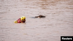 A search and rescue team member looks for bodies with the help of a dog, following torrential rains that triggered floods and mudslides, in Umbumbulu, near Durban, South Africa, April 18, 2022.