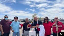 This April 2022 photo provided by Dominga Villegas shows priests, deacons and volunteers as they get ready to celebrate Palm Sunday Mass at a shelter for migrant teens in Pecos, Texas, April 10, 2022. 