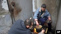 Mariupol residents cook sitting at an entrance to their damaged apartment building in an area of the city that Russian-backed separatists claim to control in the Ukraine city of Mariupol, April 13, 2022.