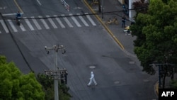 A worker wearing personal protective equipment walks on a street during a COVID-19 lockdown in the Jing'an district in Shanghai, April 12, 2022.
