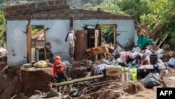 A member the South African Police Services (SAPS) Search and Rescue Unit guides a sniffer dog during search efforts to locate people who are unaccounted for from area of KwaNdengezi township outside Durban, April 15, 2022, after their homes were swept awa