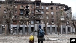 A local resident looks at a damaged during a heavy fighting apartment building in an area controlled by Russian-backed separatist forces in Mariupol, Ukraine, April 16, 2022.
