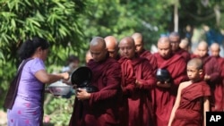 A Buddhist monk receives alms from a devotee as they collect their morning alms Thursday, April 14, 2022, in Yangon, Myanmar. (AP Photo/Thein Zaw)